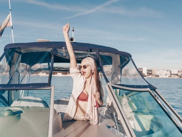 mujer con champange en embarcacion con fondo ciudad y costa
